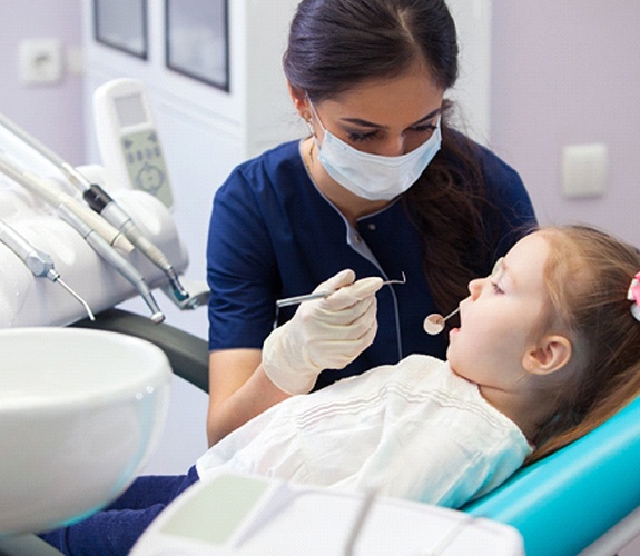Little girl having her teeth examined by a female dentist