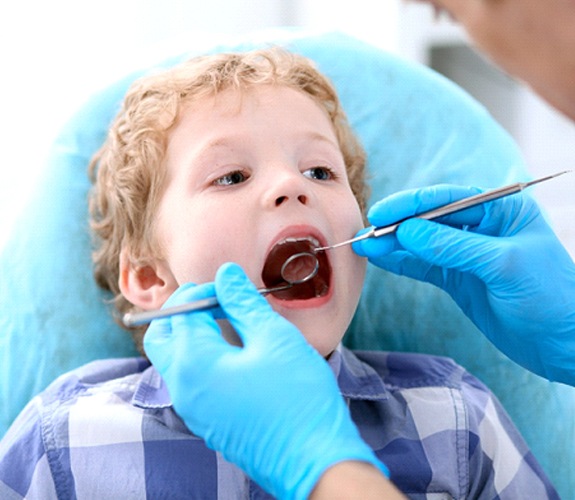 Little boy in patterned shirt having his teeth examined