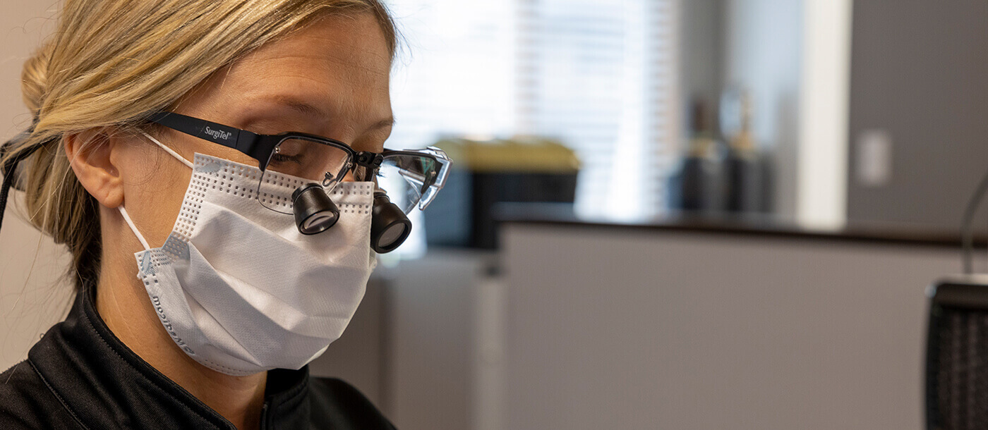 Dentist wearing protective gear to treat dental patient