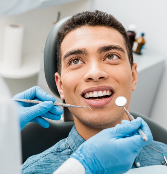 Man in dental chair smiling at dentist