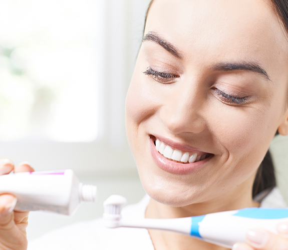 Woman brushing teeth to prevent dental emergencies