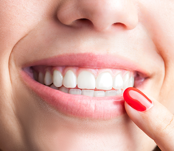 Patient pointing to smile after advanced periodontal procedures