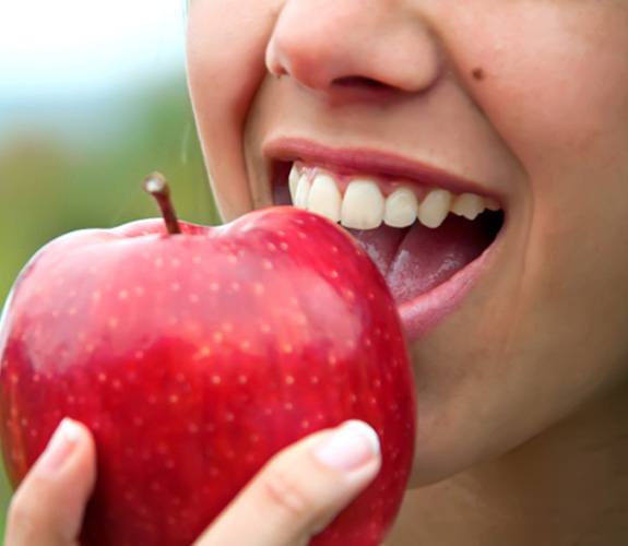 Patient with dental implants in Wilmington eating an apple