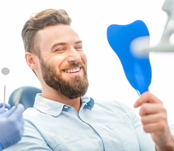 Young man admiring his new dental implants in Wilmington  