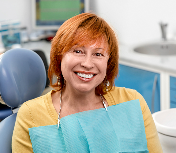 Woman sharing flawless smile after dental implant tooth replacement