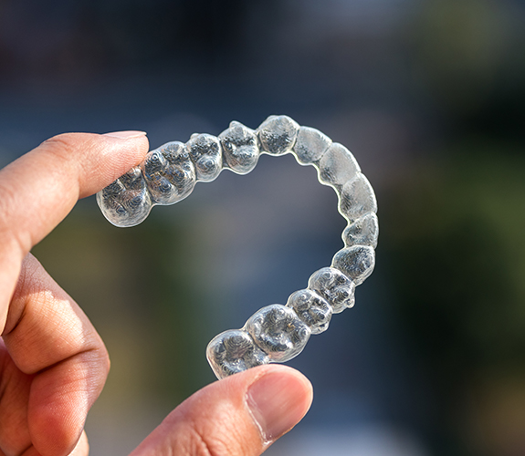 Hand holding an Invisalign tray