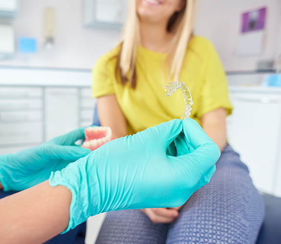 Dentist showing dental patient an Clear Aligners tray and smile model