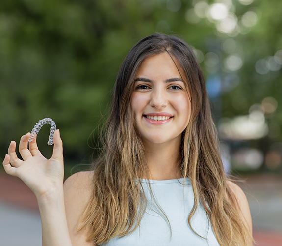 Teen girl holding an Invisalign Teen aligner tray