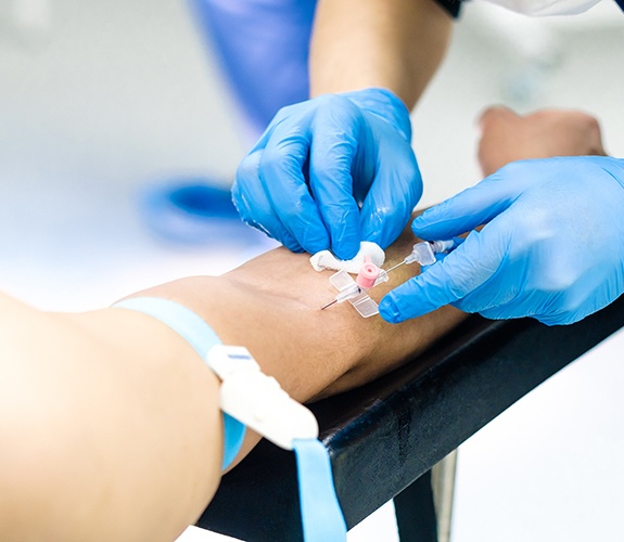 Person inserting an IV into a patient’s arm