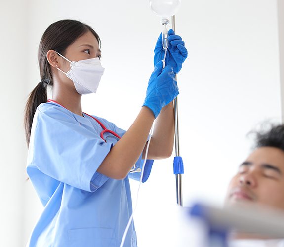 Person with their eyes closed while doctor sets up IV