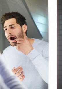 Man checking his gums in the mirror