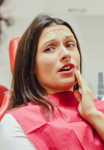 Woman in the patient’s chair describing her oral ache to her dentist