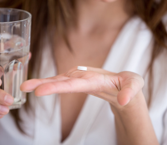Person taking a pill with water 