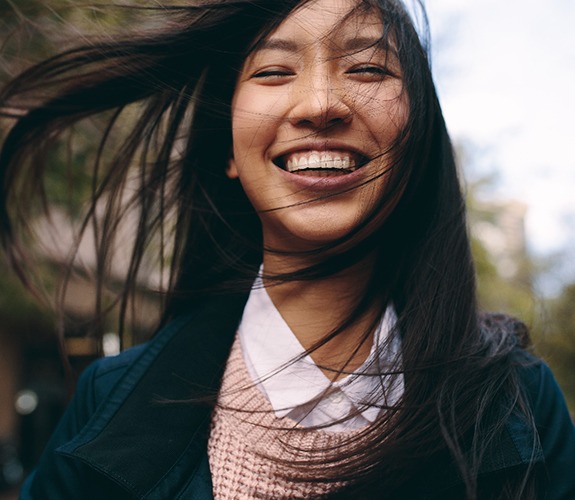 Woman outside smiling after laser treatment of gum disease in Wilmington, IL