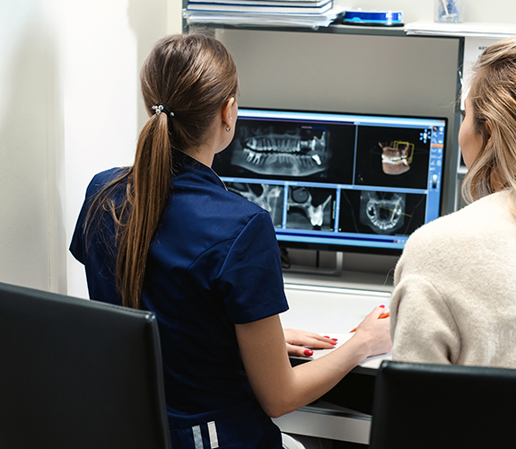 Two dental team members looking at digital x-rays