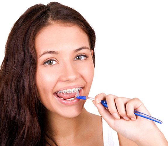 Smiling young woman cleaning beneath her braces’ wires