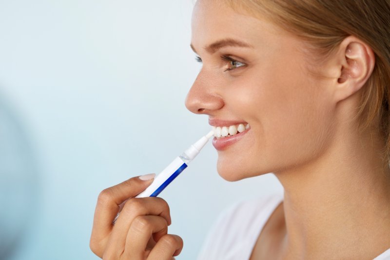 woman using a whitening pen to brighten her smile