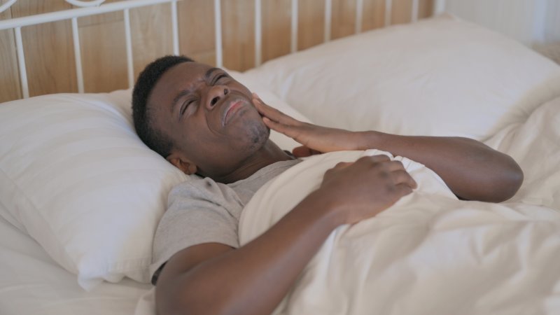 man lying down in bed with a toothache